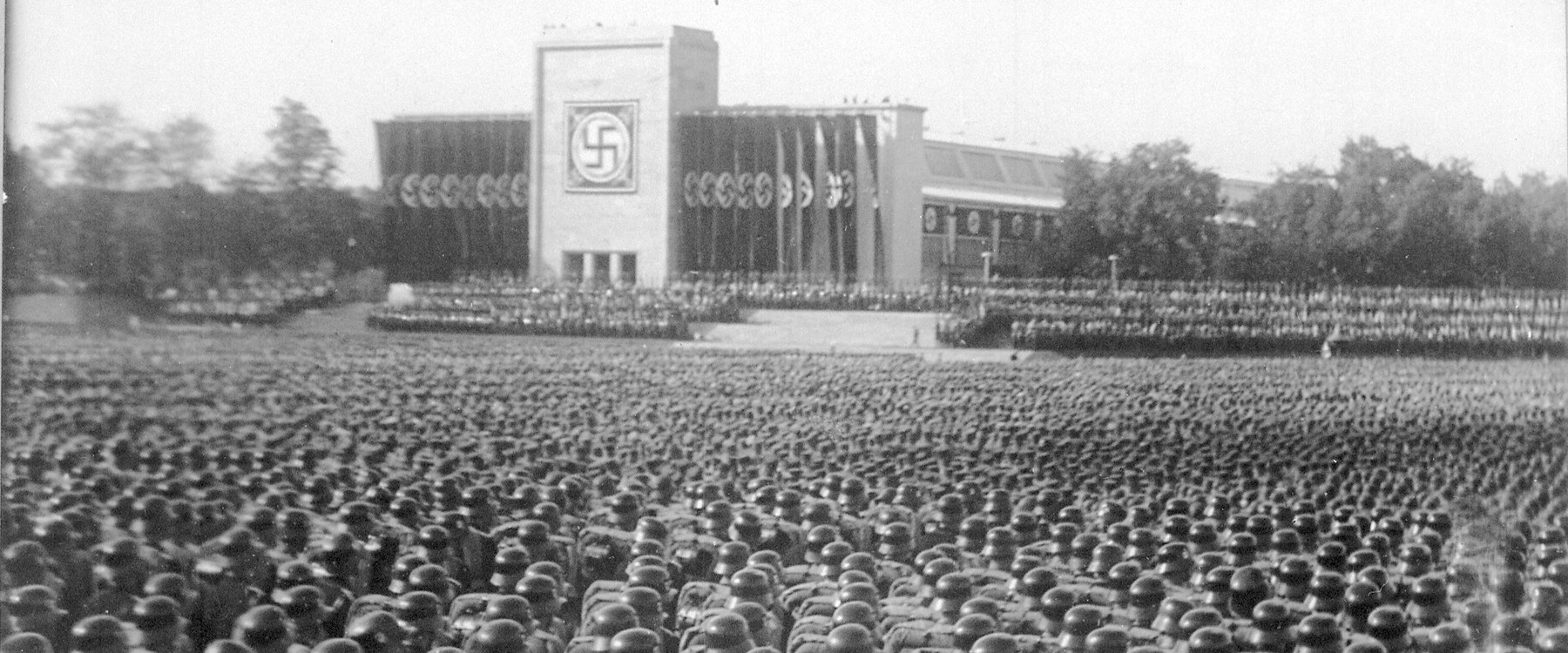 Sevřené řady mužů v přilbách na norimberském sjezdovém poli, v pozadí tribuna